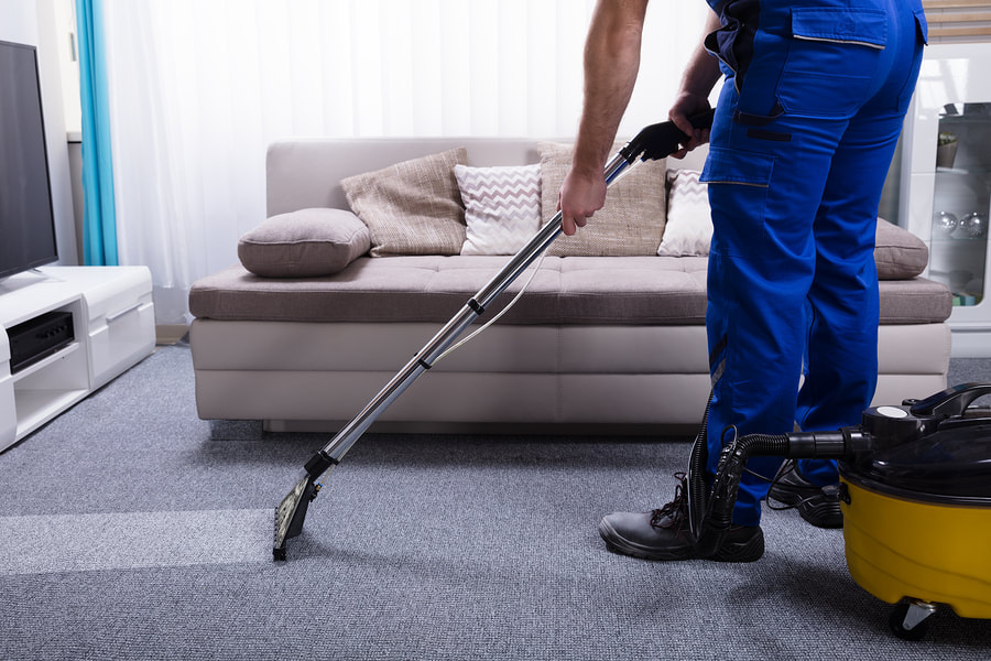 man vacuums the floor mat